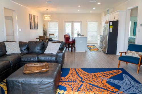 a living room with a leather couch and a table at Sunset Blessing - 207 Arias Ct in Dauphin Island