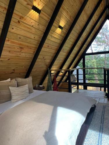 a bed in a room with a wooden ceiling at Alpina Village, Jacuzzi Climatizado, Montaña, Fogata, Jarabacoa in Jarabacoa
