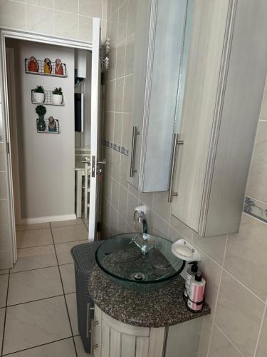 a bathroom with a glass sink and a cabinet at Sea Breeze in Mossel Bay