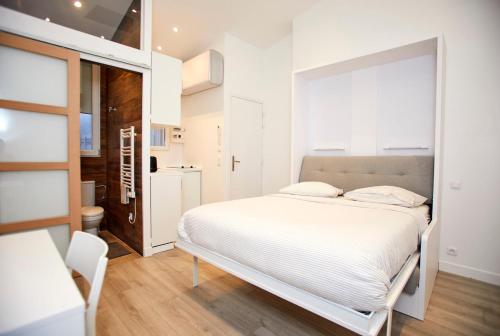 a white bedroom with a bed and a bathroom at Rempart du Chateau-SV85 StudioVincennes in Vincennes