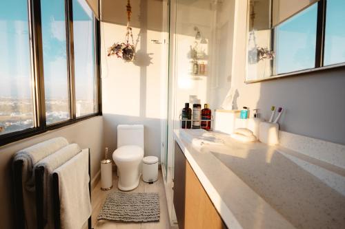 a bathroom with a sink and a toilet and windows at Volcano View Loft, Puebla Skyline1801 in Puebla