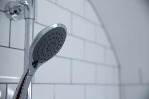 a shower head in a bathroom next to a wall at Clifton Village Apartment in Bristol