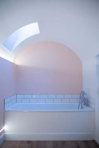 a white room with a bath tub with a window at Clifton Village Apartment in Bristol