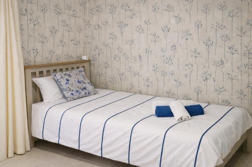 a bedroom with a bed with white sheets and blue wallpaper at Stylish Garden Apartment at Paphos Harbour in Paphos