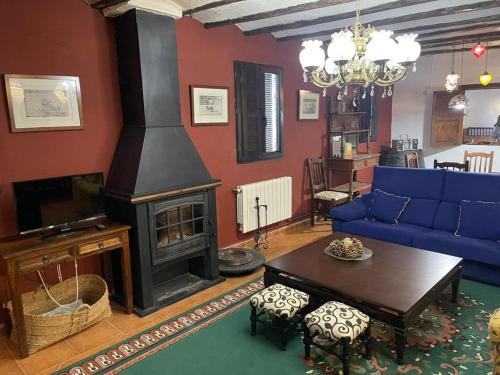 a living room with a fireplace and a blue couch at CASA RURAL VICENTA 1750 Alojamiento rural, capacidad hasta 30 personas in Albentosa