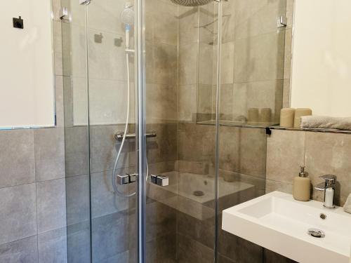a shower with a glass door next to a sink at Ferienwohnung Auszeit in den Parkvillen Carlota und Candela Baabe in Baabe