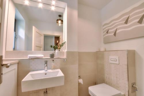 a bathroom with a sink and a toilet and a mirror at Ferienhaus Backsteinquartier D in Putbus mit Sauna und Kamin in Putbus