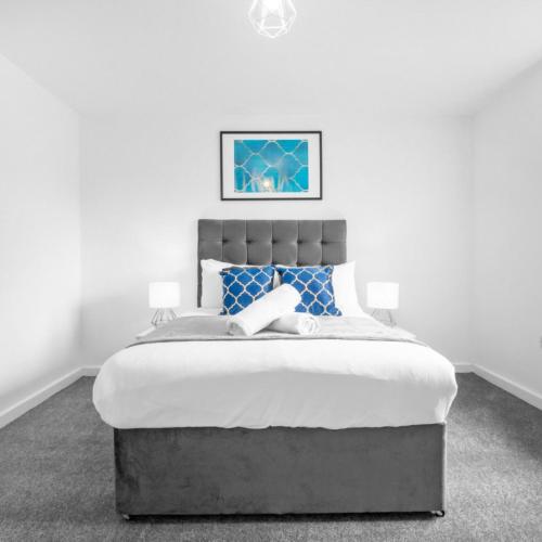 a white bedroom with a large bed with blue pillows at Modern 2 Bed Apartment - Parking - Smart TV - Fast Wi-Fi 27CR in Sleightholme