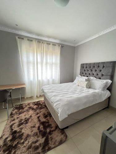 a white bedroom with a large bed and a rug at Pwake Luna Guesthouse in Swakopmund