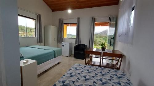 a bedroom with a bed and a desk and a table at Chalé inteiro Canto da Graúna in Ibicoara