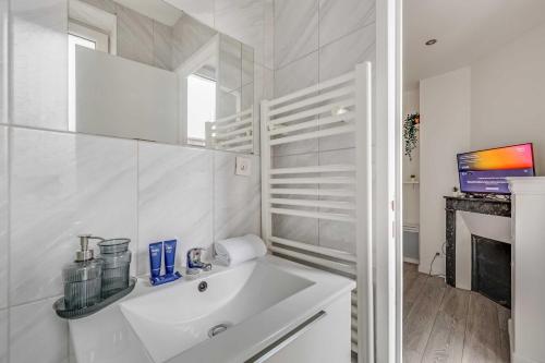 a white bathroom with a sink and a tv at Cosy Studio - 2P- Clichy in Clichy