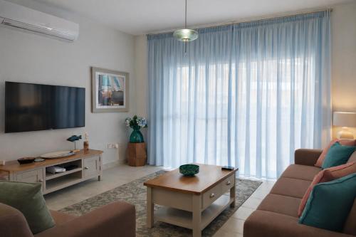 a living room with a couch and a tv at Stylish Garden Apartment at Paphos Harbour in Paphos