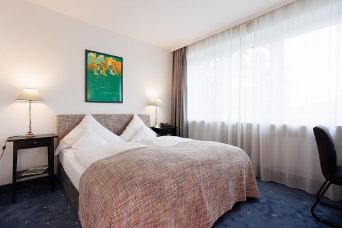a hotel room with a bed and a window at Hotel Nymphenburg City - München in Munich