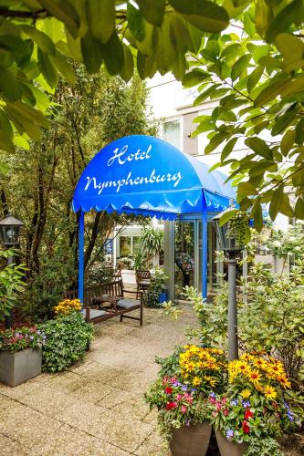 a blue umbrella in a garden with flowers at Hotel Nymphenburg City - München in Munich