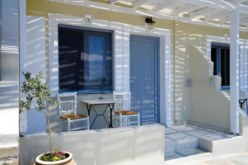 a house with two chairs and a table on the front porch at Villa Alisachni Andros in Agia Eleousa