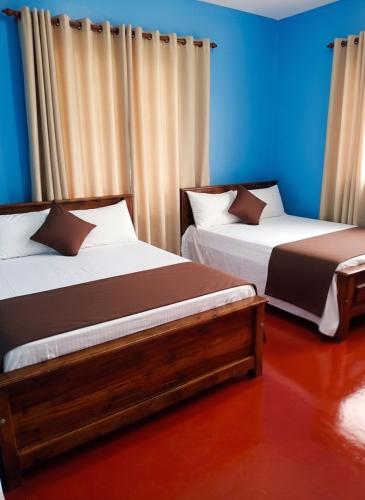 two beds in a room with blue walls at Daya Guest House in Pattipola