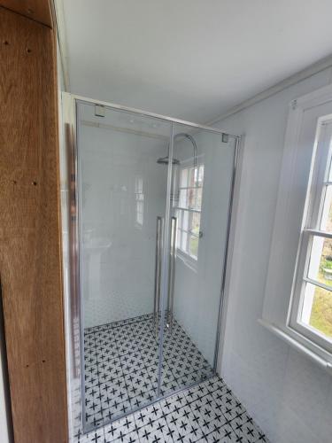 a shower with a glass door in a bathroom at Viveash - Historic accommodation with Ensuite in Hoddy Well