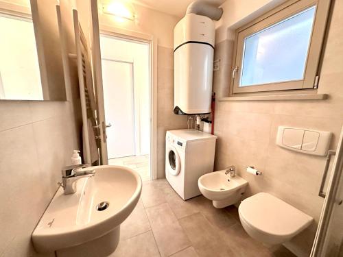 a bathroom with a sink toilet and a washing machine at Iseo Panorama Suite in Parzanica