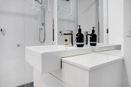 a white bathroom with two sinks and a shower at Atlantis - Coastal Retreat near Horseshoe Bay in Port Elliot