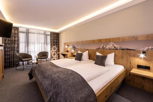 a hotel room with a large bed and a desk at Hotel AlpinaRos in Berchtesgaden