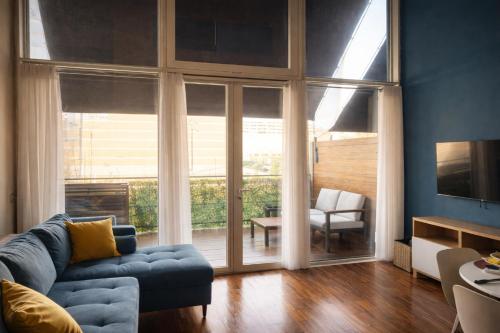 a living room with a blue couch and a large window at Easy Loft Milano in Crescenzago