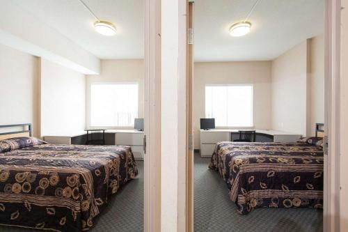 a hotel room with two beds and two windows at Residence & Conference Centre - Kitchener-Waterloo in Kitchener