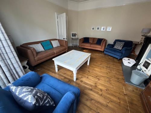a living room with blue couches and a coffee table at Beautiful Tenby House, sleeps 10, pets allowed in Tenby