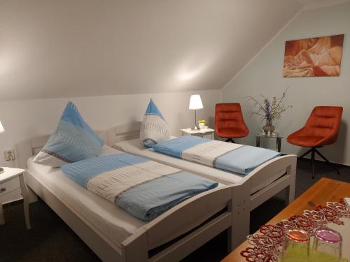 two beds in a room with red chairs and a table at Pension Renate Braun in Gamstädt