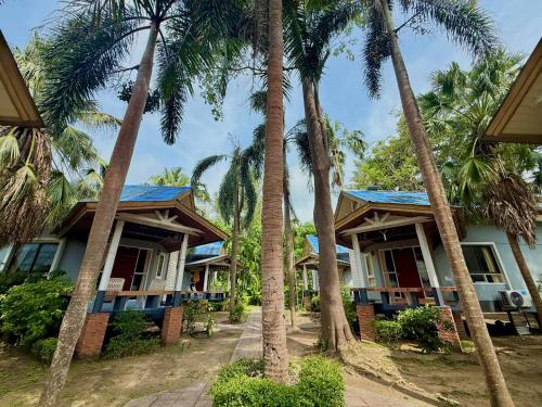 a row of palm trees in front of a house at Lanta Palm Beach Resort , Beach Bungalow - Koh Lanta in Ko Lanta