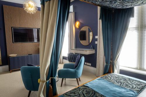a bedroom with a bed and two chairs and a mirror at Herriots Hotel in Skipton