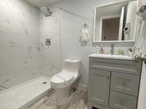 a white bathroom with a toilet and a sink at Beach Front Resort with Ocean View in Daytona Beach