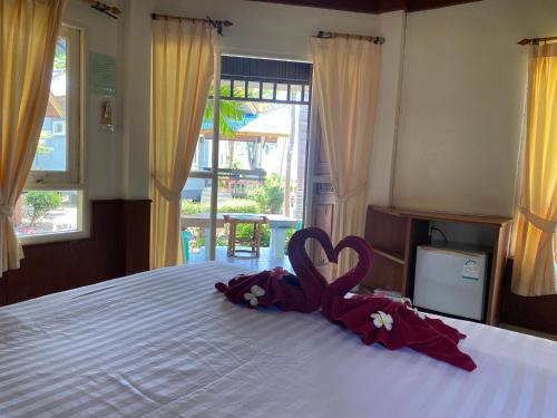a bed with a pair of towels in the shape of a heart at Lanta Palm Beach Resort , Beach Bungalow - Koh Lanta in Ko Lanta