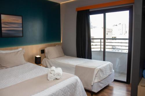 a hotel room with two beds and a balcony at Minas Garden Hotel in Poços de Caldas