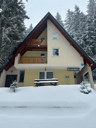a house with a balcony and a bench in the snow at Vikendica Anja in Vlasic