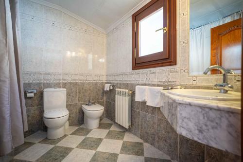 a bathroom with a toilet and a sink and a tub at Hotel del Pastor in Morella
