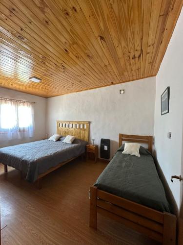 a bedroom with two beds and a wooden ceiling at Casa de Descanso Don Abel in Chascomús