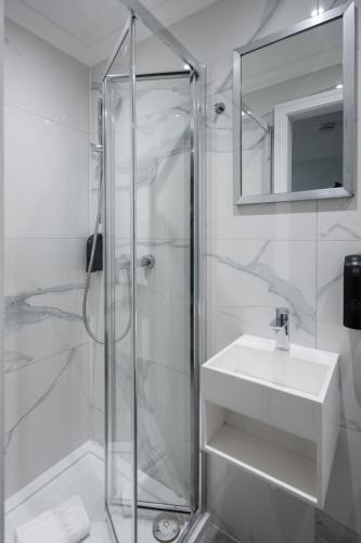 a white bathroom with a shower and a sink at MSK Elite in London