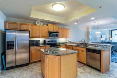 a kitchen with wooden cabinets and stainless steel appliances at Wave Watcher - Holiday Isle #609 in Dauphin Island