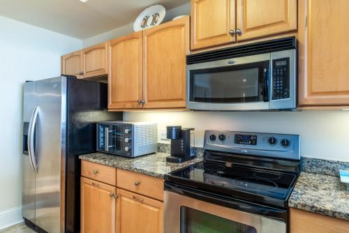 a kitchen with stainless steel appliances and wooden cabinets at Wave Watcher - Holiday Isle #609 in Dauphin Island