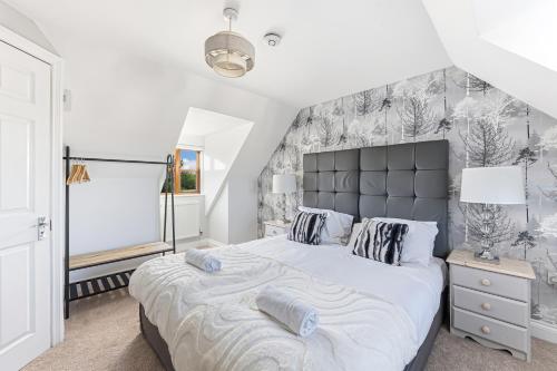 a bedroom with a large bed with a large headboard at Loughton House - Central Location - Driveway Parking, Self-Check-In, Garden, Super-Fast Wifi and Smart TVs by Yoko Property in Milton Keynes