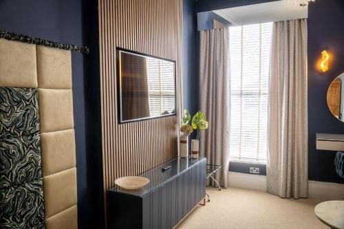 a blue room with a dresser and a window at Herriots Hotel in Skipton