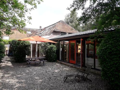 a patio with an umbrella and a table and bench at Toplocatie voor je workshop! Of grote gezin! Zwembad! in Hurwenen
