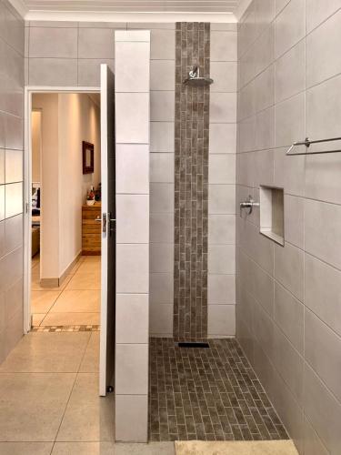a shower with a glass door in a bathroom at 10 on Sysie in Sedgefield