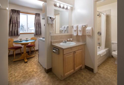a bathroom with a sink and a toilet and a table at Rocky Mountain Ski Lodge in Canmore