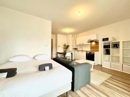 a bedroom with a large bed and a kitchen at L'Émeraude - Proche Hôpital - Parking - Clim - Fibre - Terrasse in Mont-de-Marsan