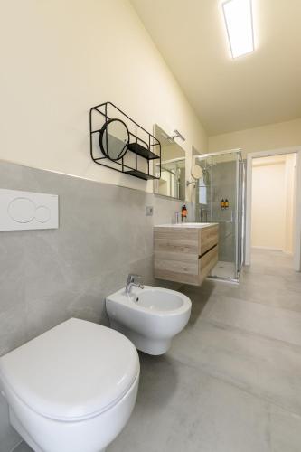 a white bathroom with a toilet and a sink at Hillside House Sant'Andrea in Vittorio Veneto