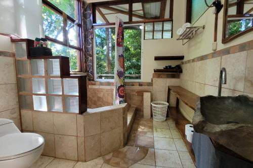 a bathroom with a tub and a toilet and windows at Nature Lovers Quepos in Quepos