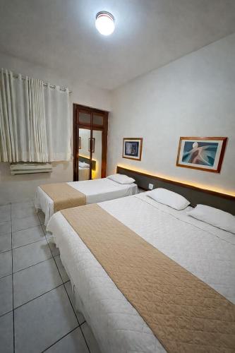 a hotel room with three beds and a window at Flat central com estacionamento in Ribeirão Preto