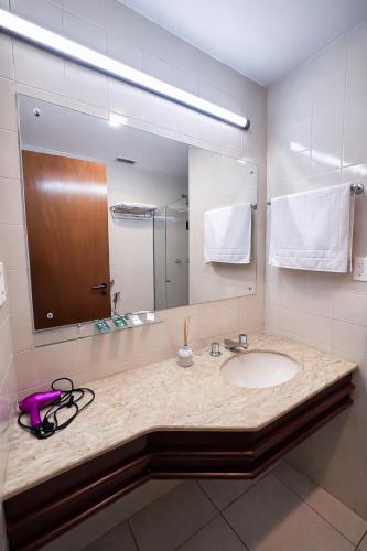 a bathroom with a sink and a large mirror at Flat central com estacionamento in Ribeirão Preto