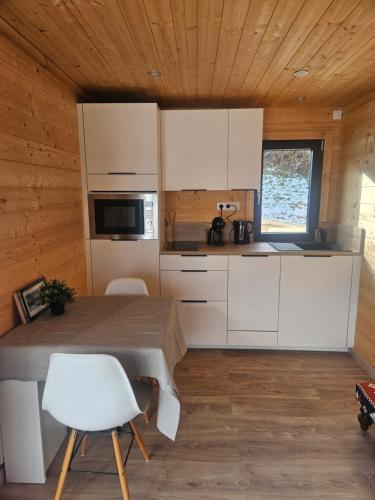 Le Petit Chalet في سان جوريوز: مطبخ ذو خزائن بيضاء وطاولة في غرفة